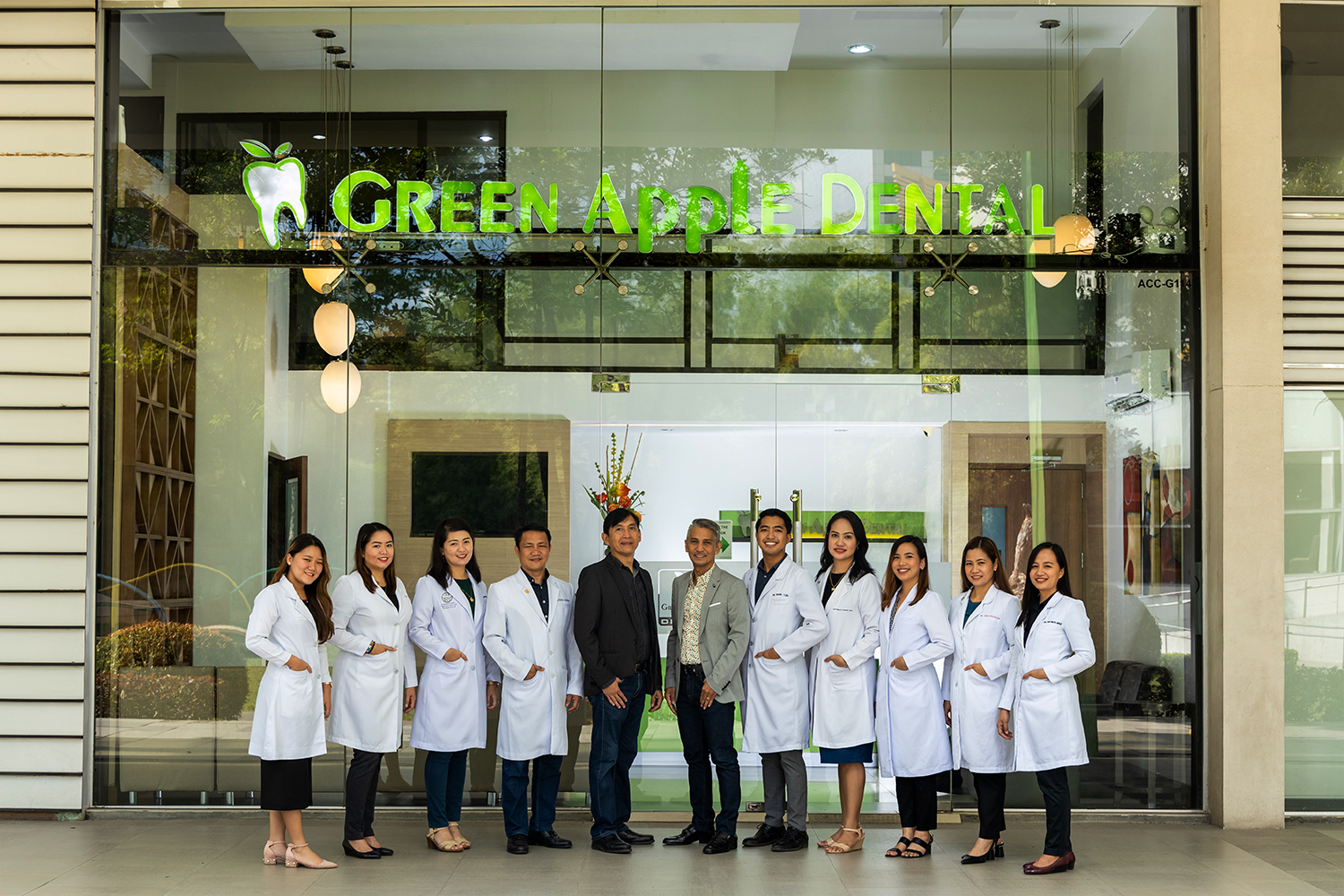 Green Apple Dental Cebu clinic team photographed outside the clinic entrance beneath the Green Apple Dental sign.